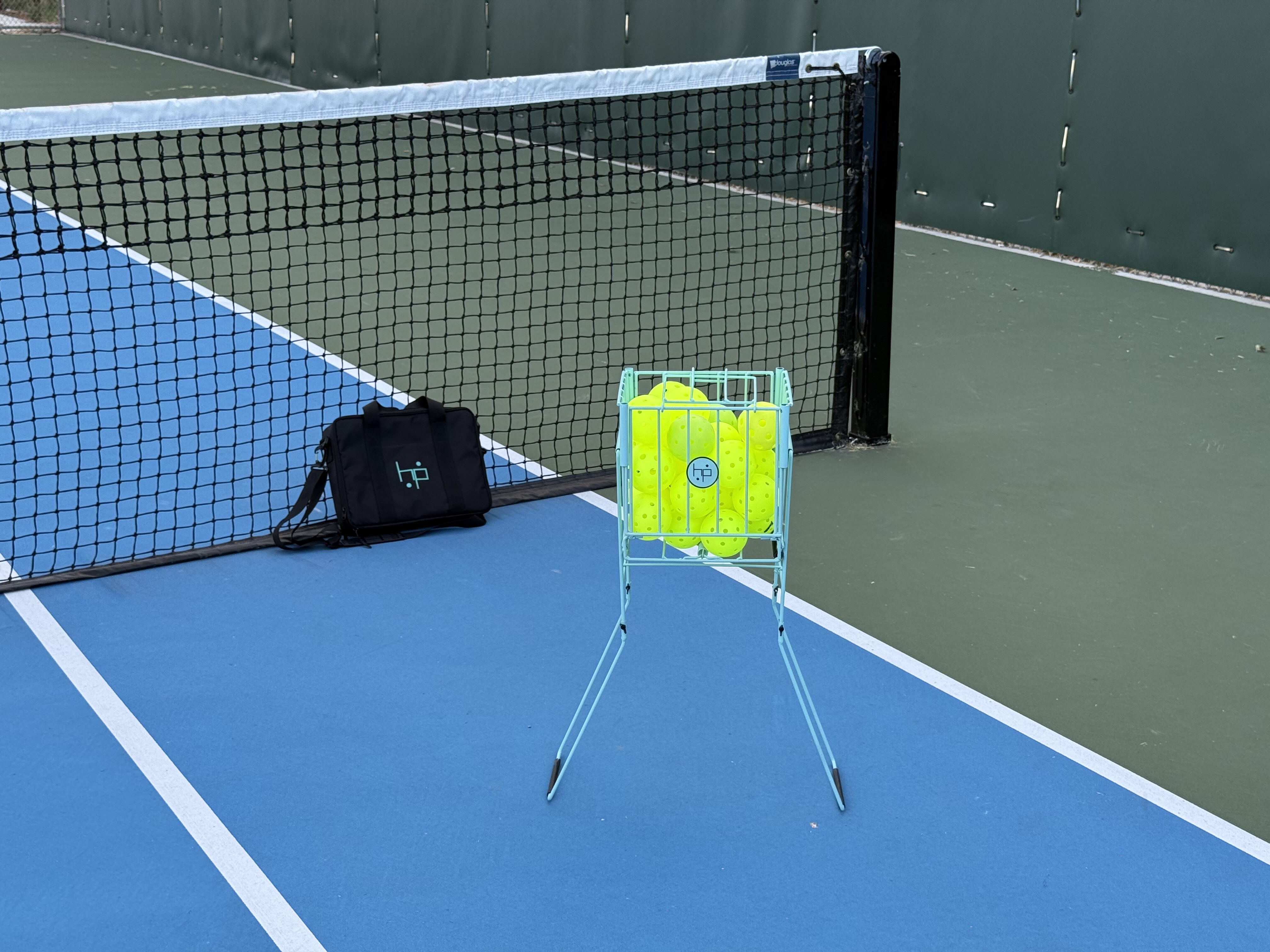BallHP MS hopper filled with yellow pickleballs on a blue court