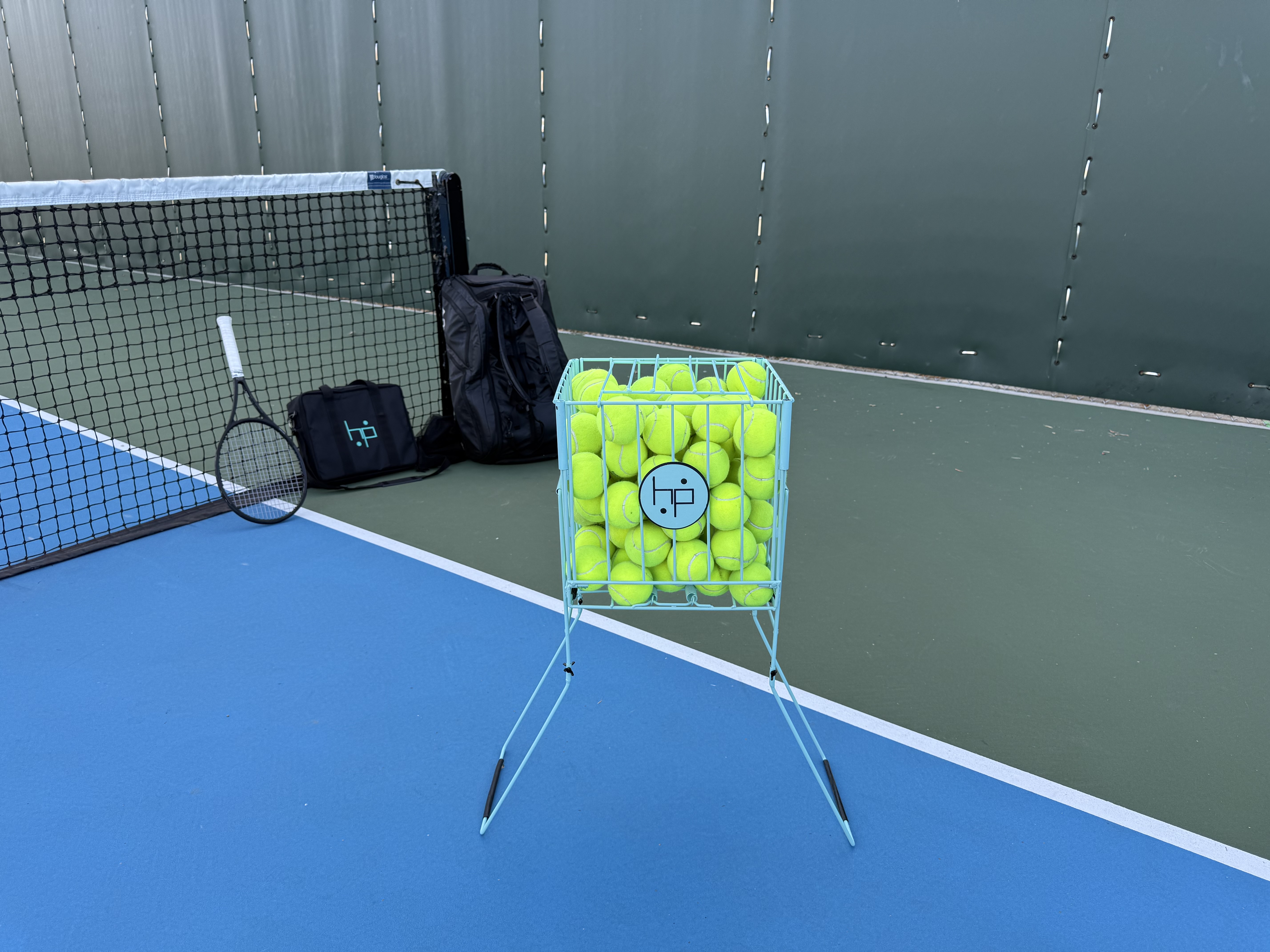 BallHP XL hopper filled with tennis balls on a blue hard court
